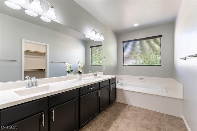 bathroom featuring a sink, a walk in closet, a garden tub, and double vanity