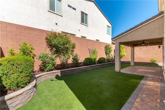 view of yard with a fenced backyard, a ceiling fan, and a patio area