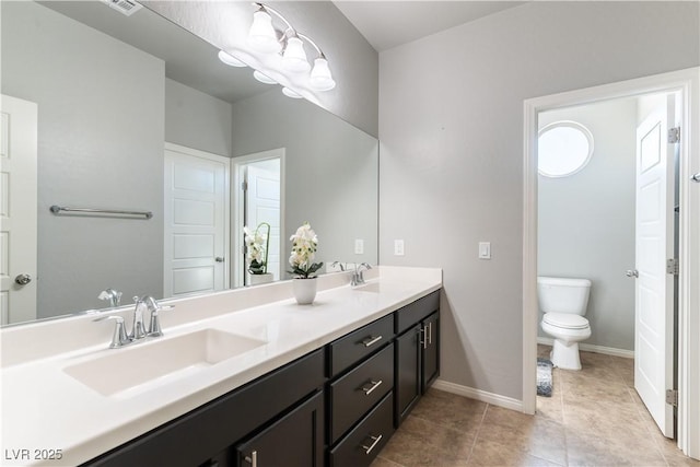 full bathroom featuring double vanity, toilet, baseboards, and a sink