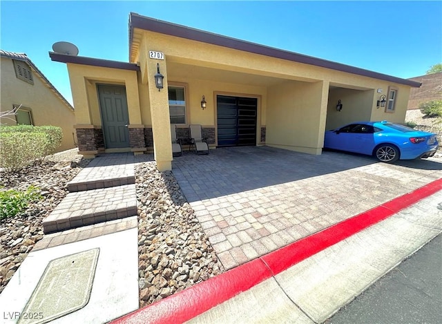 view of front of home with stucco siding, decorative driveway, and stone siding