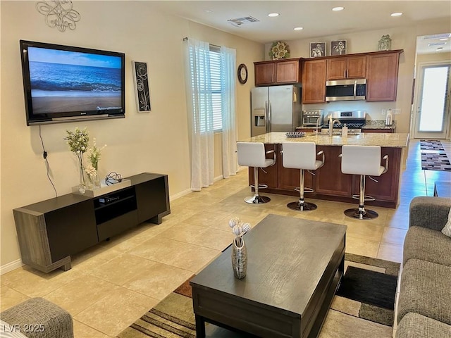 living room featuring baseboards, visible vents, plenty of natural light, and light tile patterned floors
