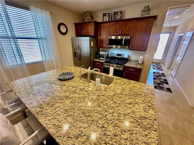 kitchen featuring a breakfast bar area, visible vents, a sink, light tile patterned floors, and stainless steel appliances