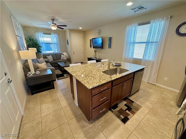 kitchen featuring light tile patterned flooring, light stone counters, a sink, dishwasher, and visible vents