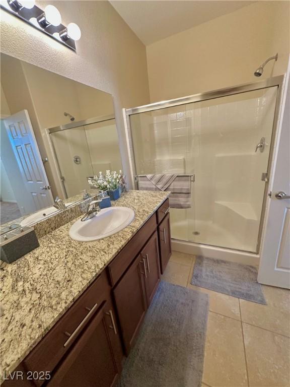 bathroom with vanity, tile patterned flooring, and a shower stall