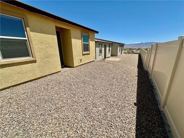 view of property exterior featuring a mountain view, a fenced backyard, a patio area, and stucco siding
