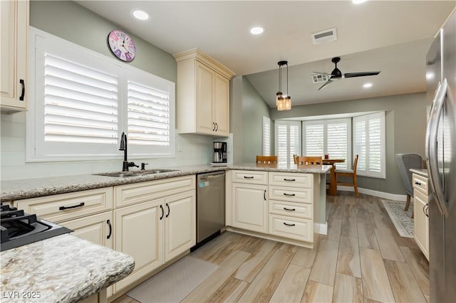 kitchen featuring a sink, appliances with stainless steel finishes, a peninsula, and a healthy amount of sunlight