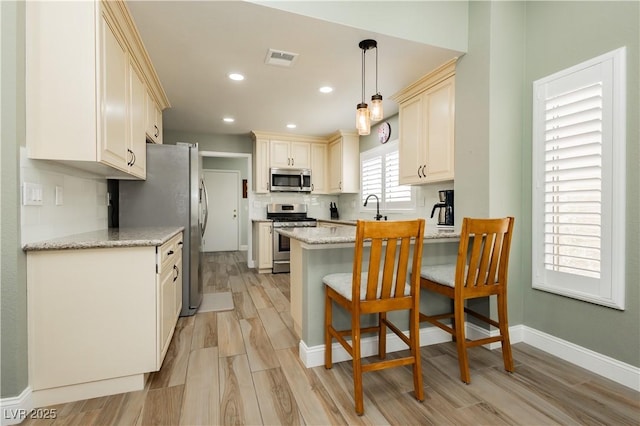 kitchen with visible vents, a peninsula, light wood-style floors, stainless steel appliances, and recessed lighting