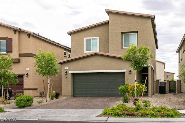view of front facade with stucco siding, an attached garage, and decorative driveway