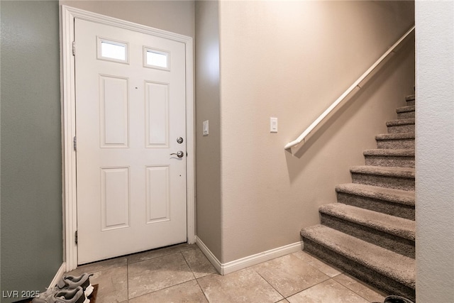 entrance foyer featuring baseboards, light tile patterned floors, and stairway