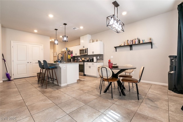 kitchen featuring stainless steel appliances, visible vents, a center island with sink, and light tile patterned floors