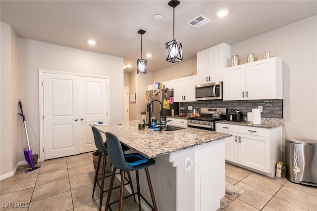 kitchen featuring light tile patterned floors, decorative backsplash, stainless steel appliances, and white cabinetry