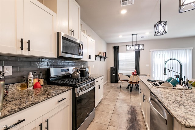 kitchen featuring appliances with stainless steel finishes, a sink, white cabinetry, tasteful backsplash, and visible vents