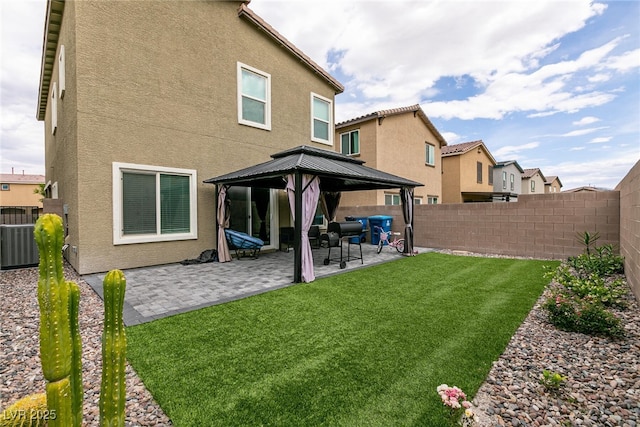 rear view of property with a fenced backyard, a patio, a gazebo, and stucco siding