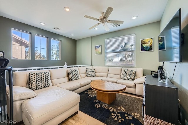 living room with a ceiling fan, visible vents, and plenty of natural light