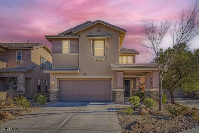 view of front of home featuring an attached garage, driveway, stone siding, and stucco siding