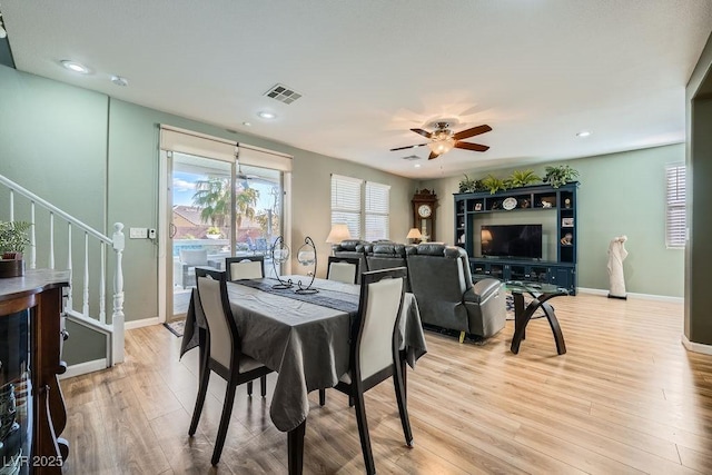 dining space with ceiling fan, light wood finished floors, stairs, baseboards, and visible vents