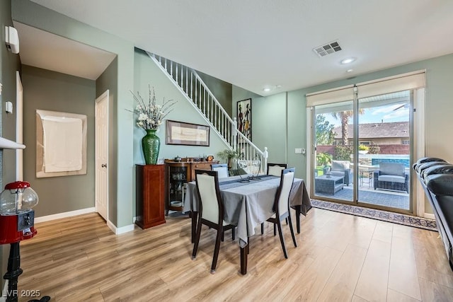 dining space with baseboards, visible vents, stairway, and light wood-style floors