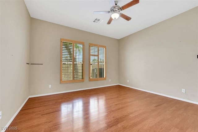 spare room featuring visible vents, baseboards, ceiling fan, and wood finished floors