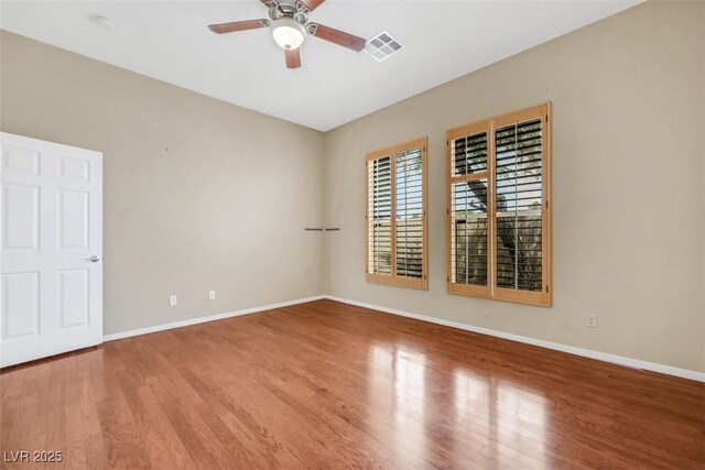 spare room featuring baseboards, a ceiling fan, wood finished floors, and visible vents