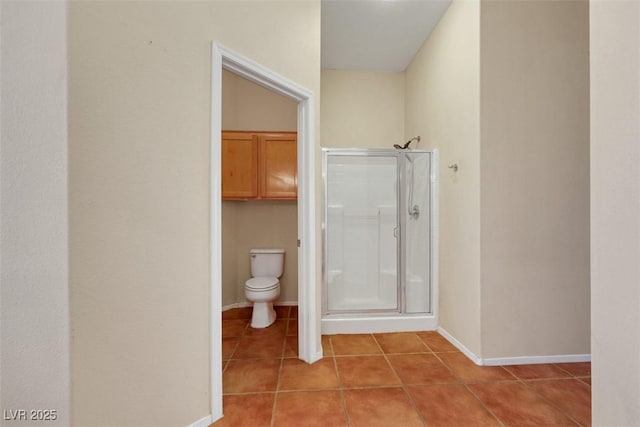 full bath featuring tile patterned floors, baseboards, a shower stall, and toilet
