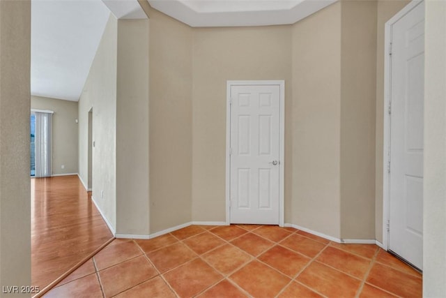 corridor with light tile patterned floors and baseboards