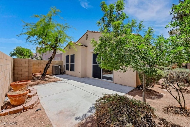 back of property with a patio, central AC unit, a fenced backyard, and stucco siding