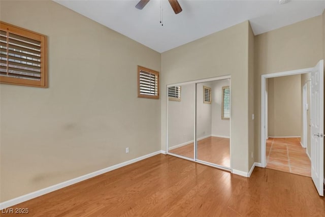 unfurnished bedroom with baseboards, ceiling fan, a closet, and wood finished floors
