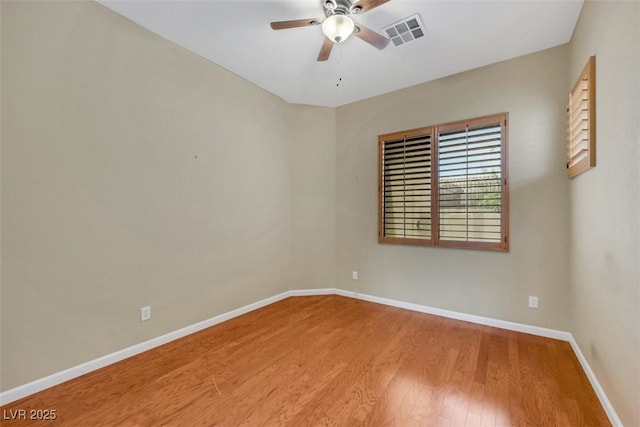 unfurnished room with baseboards, a ceiling fan, wood finished floors, and visible vents
