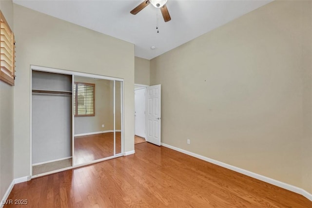 unfurnished bedroom with baseboards, ceiling fan, wood finished floors, and a closet