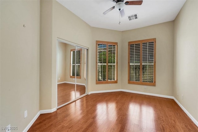 spare room featuring baseboards, ceiling fan, wood finished floors, and visible vents