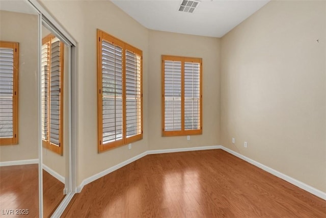 spare room featuring visible vents, baseboards, and wood finished floors