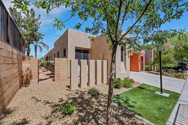 view of side of property with stucco siding, fence, and concrete driveway