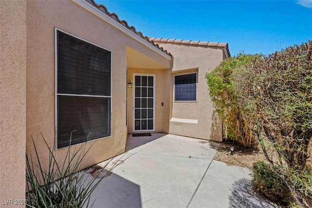 view of exterior entry with a patio area and stucco siding