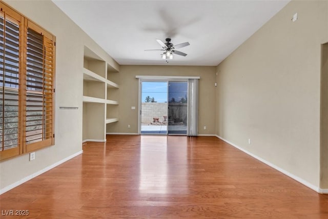 unfurnished living room with baseboards, a ceiling fan, built in features, and wood finished floors
