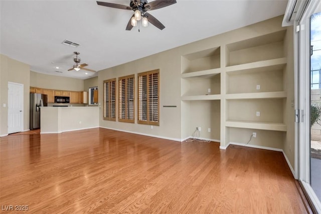 unfurnished living room featuring a ceiling fan, visible vents, built in features, baseboards, and light wood-style flooring