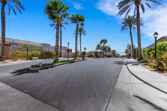 view of street featuring street lighting, curbs, a gate, sidewalks, and a residential view