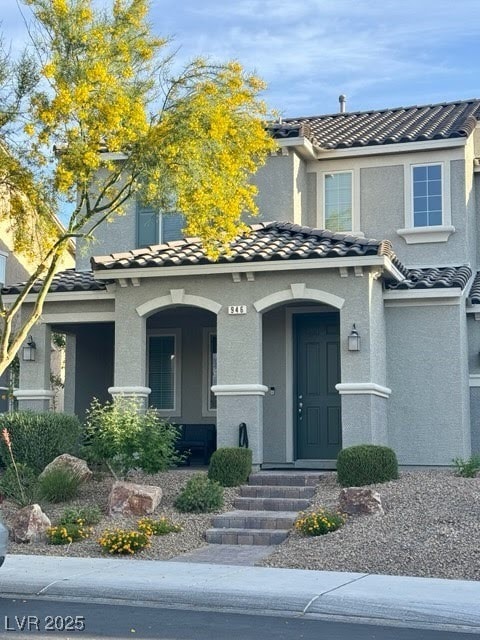 view of front facade featuring a tiled roof, a porch, and stucco siding