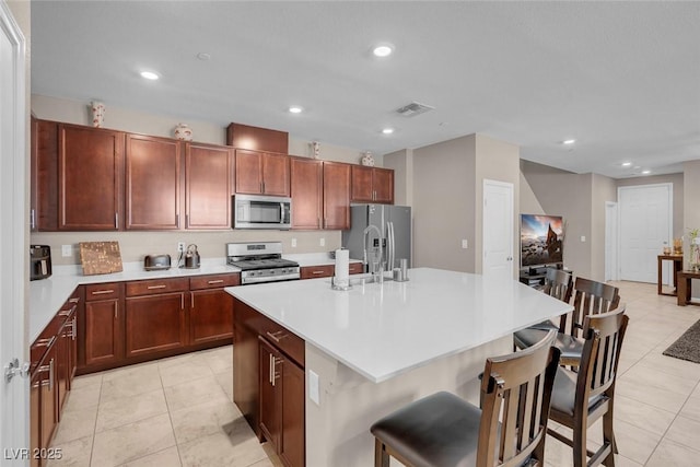 946 Belton Lake Ave, North Las Vegas, NV 89086 - kitchen featuring light tile patterned floors, an island with sink, stainless steel appliances, and visible vents