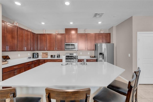946 Belton Lake Ave, North Las Vegas, NV 89086 - kitchen with visible vents, a kitchen island with sink, light tile patterned flooring, light countertops, and appliances with stainless steel finishes