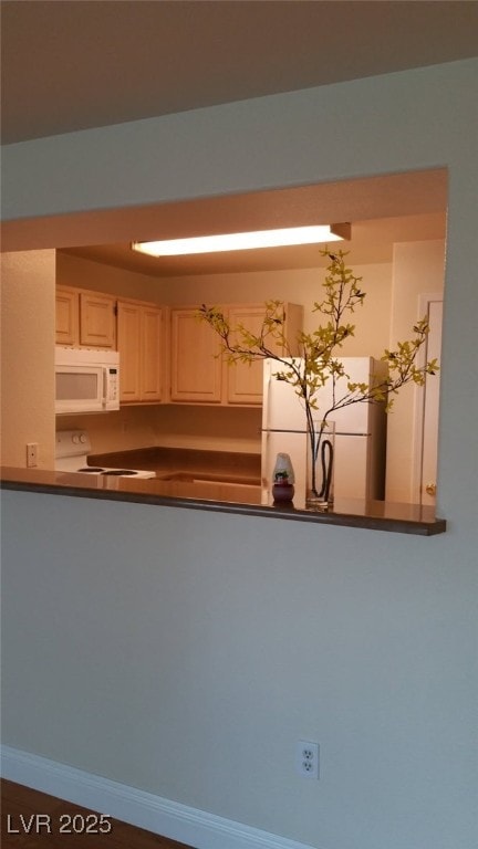 kitchen with white appliances, dark countertops, and baseboards