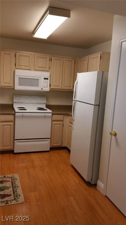 kitchen with white appliances, dark countertops, and light wood-style flooring