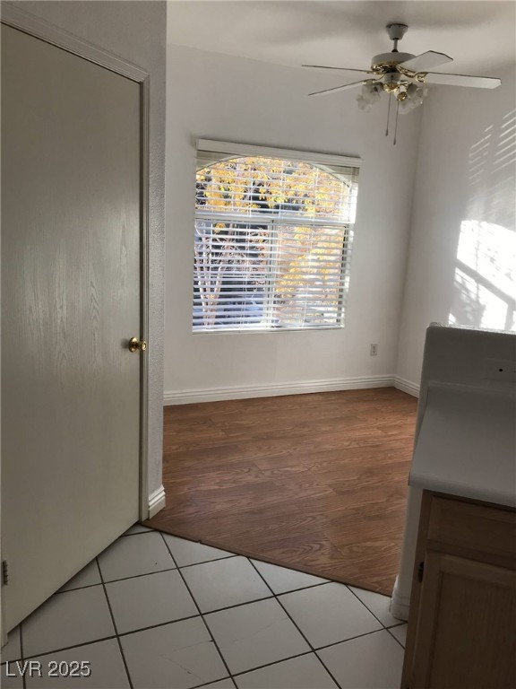 unfurnished dining area with baseboards, a ceiling fan, and light wood finished floors