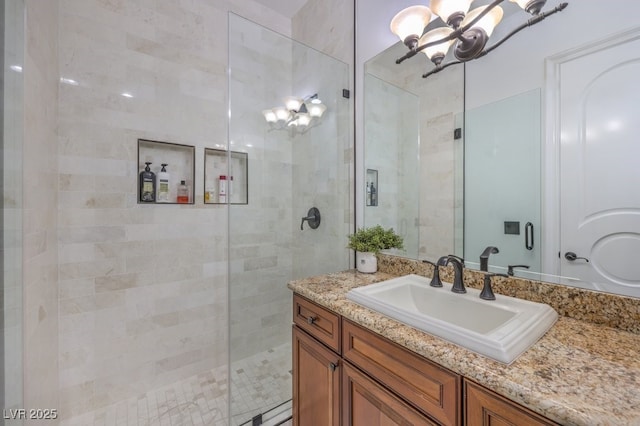 full bath with an inviting chandelier, vanity, and tiled shower