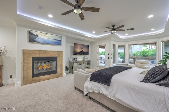 carpeted bedroom with a ceiling fan, visible vents, a tiled fireplace, a raised ceiling, and recessed lighting