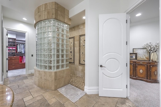 bathroom featuring stone tile floors, recessed lighting, baseboards, and walk in shower