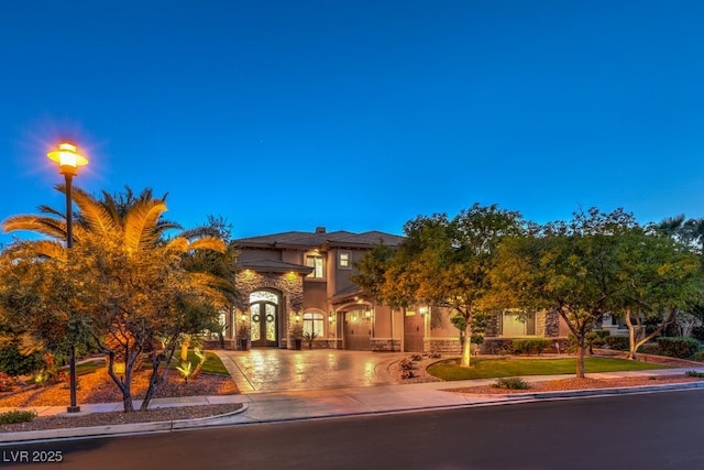 view of front facade with curved driveway, stone siding, and stucco siding