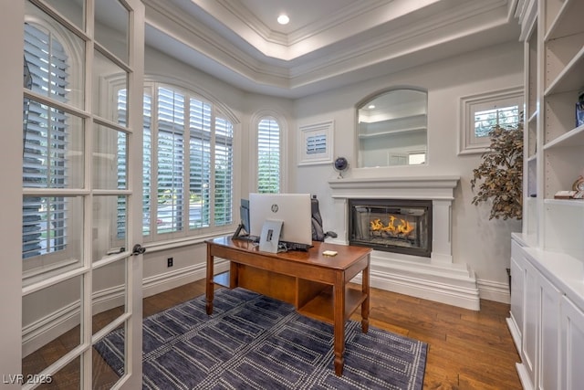 home office with crown molding, baseboards, a glass covered fireplace, and dark wood-type flooring
