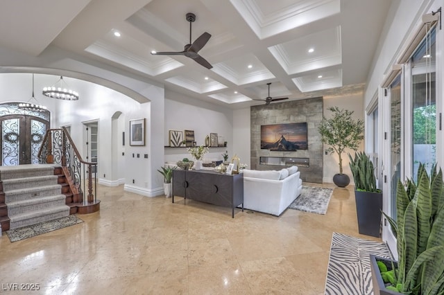 living area with arched walkways, baseboards, plenty of natural light, and ceiling fan with notable chandelier