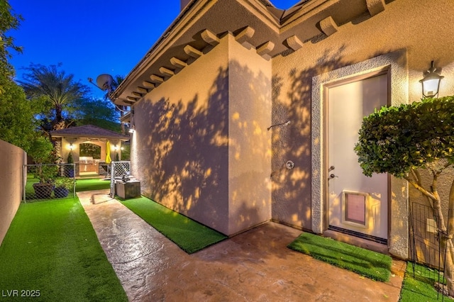 doorway to property featuring fence and stucco siding