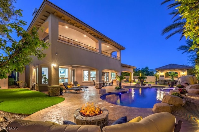 pool at night featuring a fenced in pool, a patio area, and an outdoor living space with a fire pit